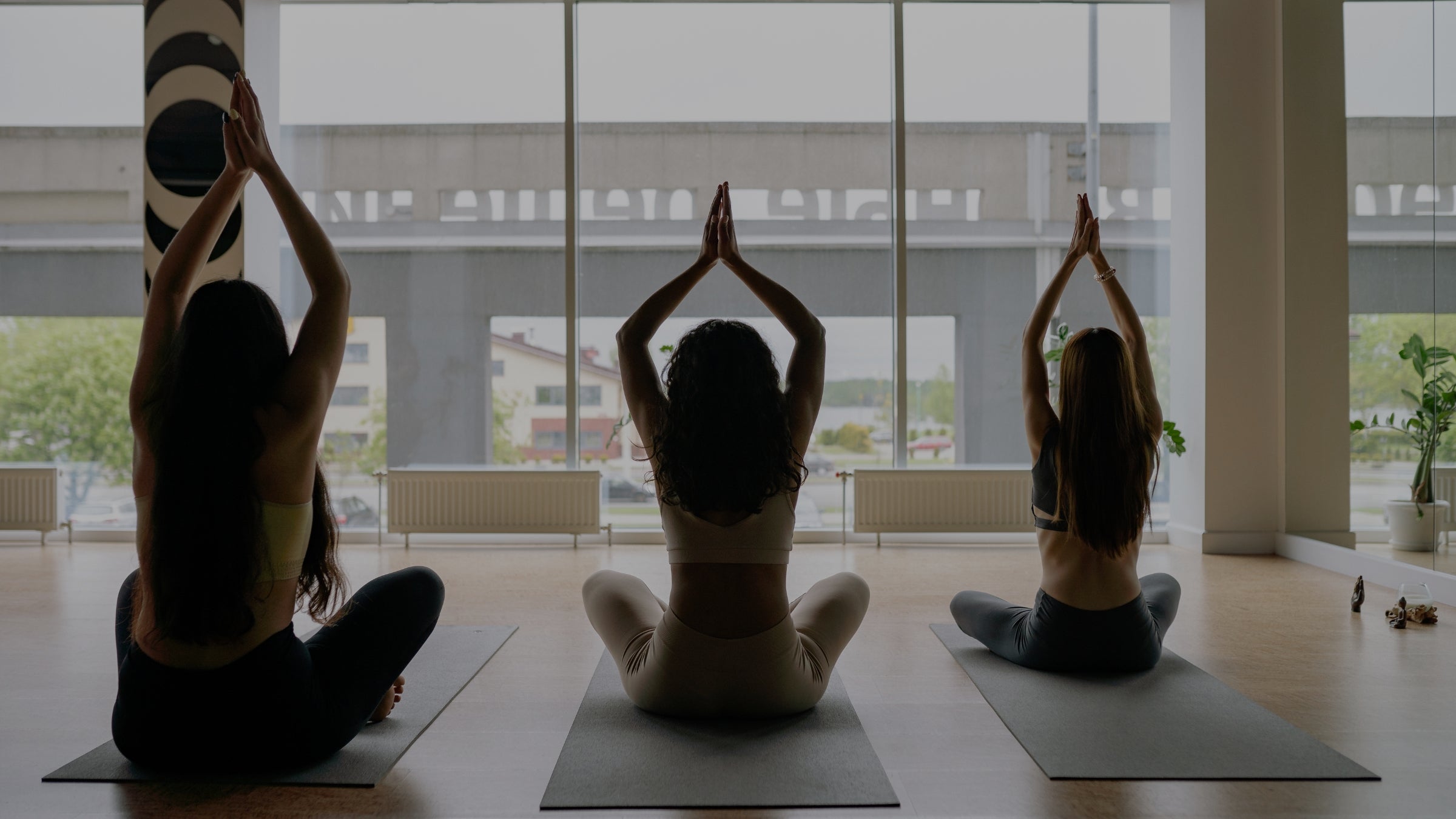 Three people practicing yoga in a modern indoor setting with large windows.